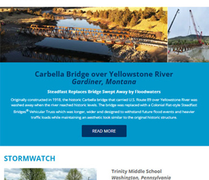 Two women sit on a bench at a bus stop, one looking at her phone, with city buildings and trees in the background.