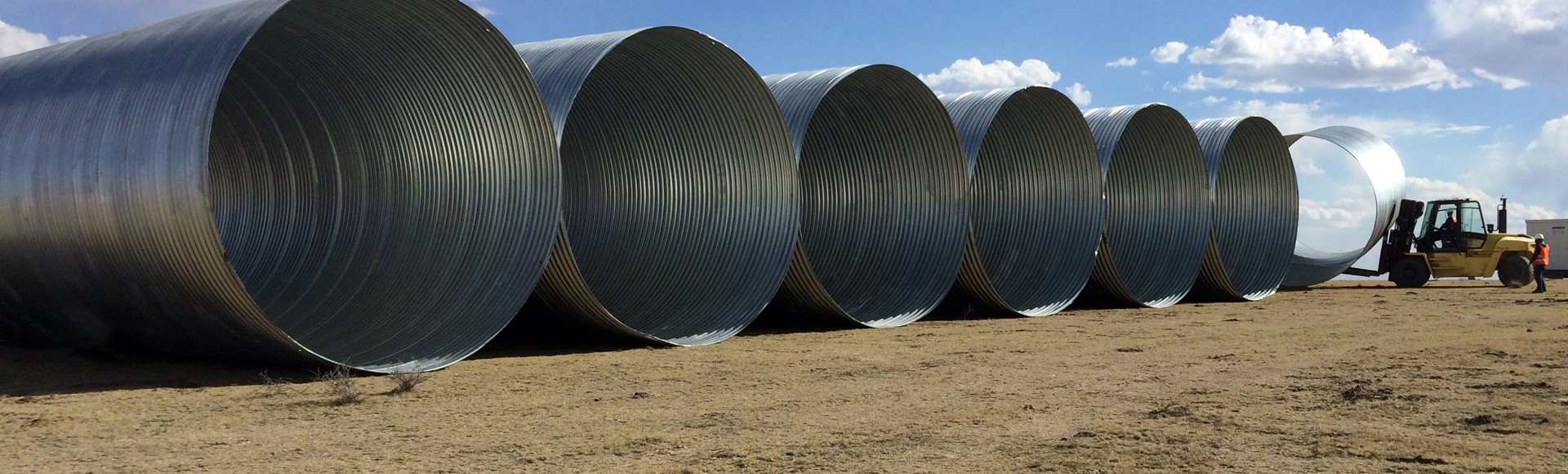 Large diameter corrugated steel pipe staged for installation. 