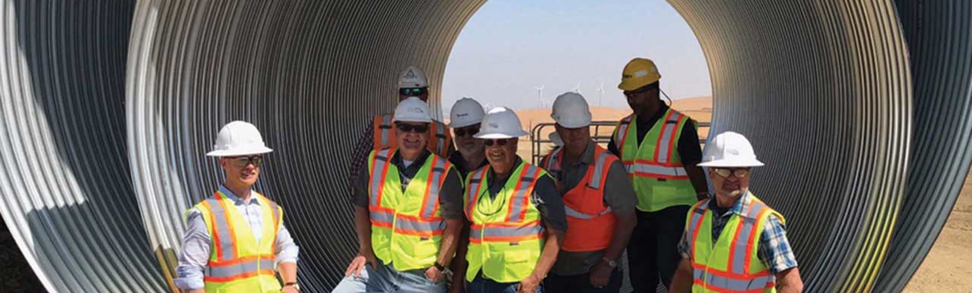 Contech employees standing inside a large-diameter corrugated metal pipe. 
