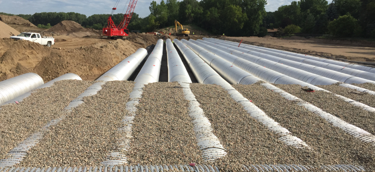 A Contech corrugated metal pipe stormwater detention system being backfilled.