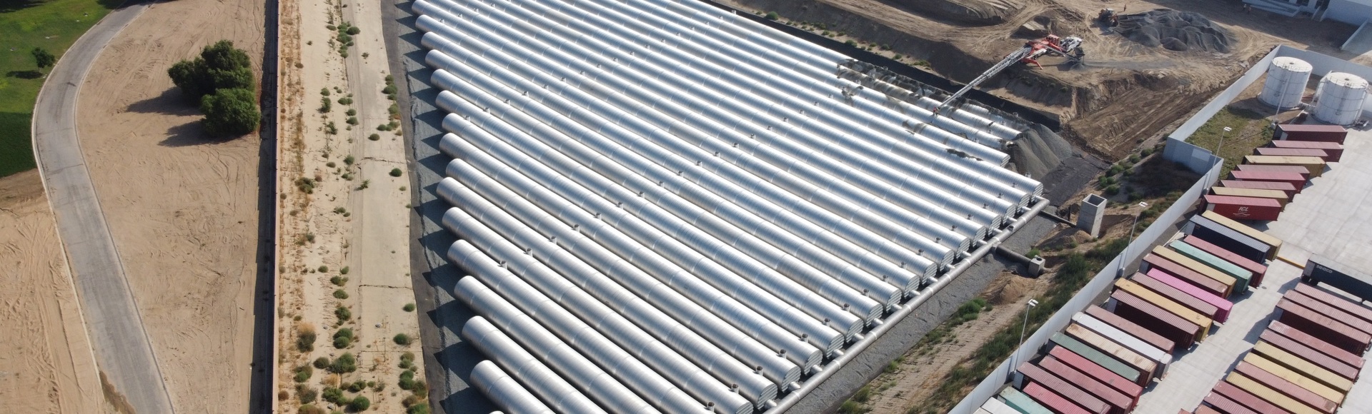 An aerial view of a large corrugated metal pipe stormwater detention system. 