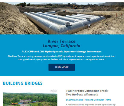 Large stormwater pipes installed underground at a construction site with workers and equipment visible in the background.