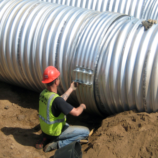 Installation of hugger bands on corrugated metal pipe. 