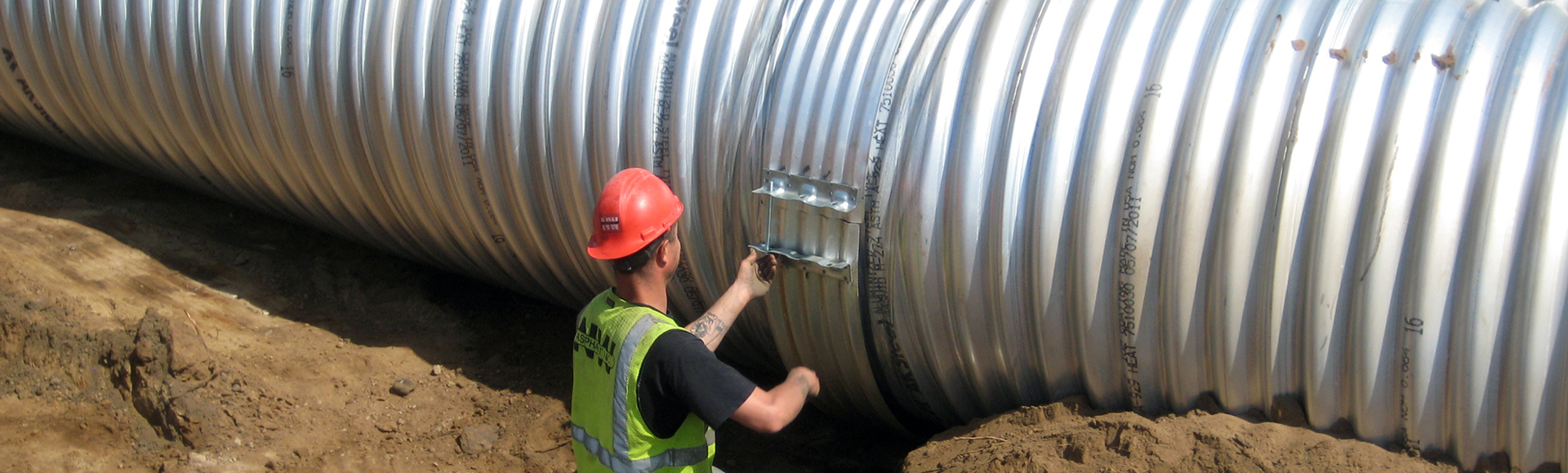 Installation of hugger bands on corrugated metal pipe. 